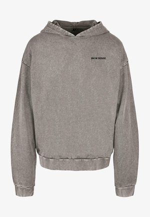 Šedá mikina s kapucí a uvolněným střihem. Má přední kapsu, žebrované manžety a malé černé logo na hrudi. Jemná textura.