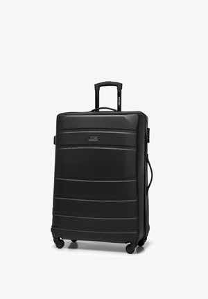 Valigia nera rigida con linee orizzontali in rilievo, manico retrattile, quattro ruote lisce e un manico laterale.