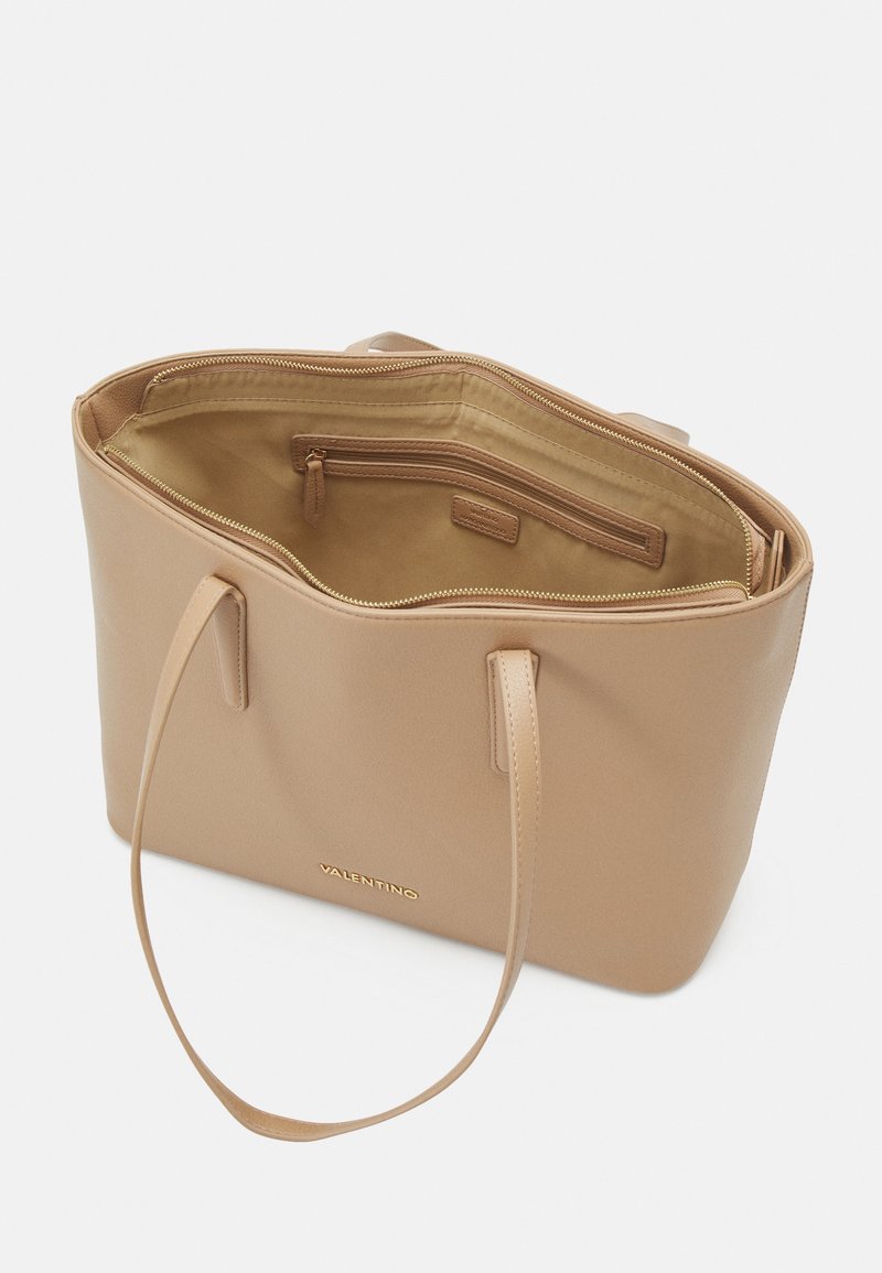 Borsa a tracolla in pelle tan con due manici, chiusura con zip e tasca interna con zip. Texture liscia e design minimalista. Dettaglio del logo dorato sul davanti.