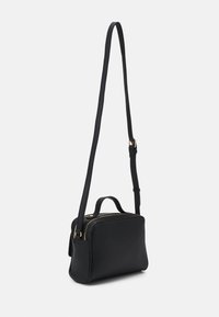 Sac bandoulière en cuir noir à la forme structurée, avec deux compartiments zippés et une courte poignée supérieure. Comprend une longue bandoulière réglable.