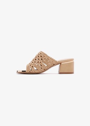Sandalias deslizantes tejidas en color beige con puntera abierta y tacón bloque estructurado. Presentan un diseño trenzado con acentos suaves y una suela plana.