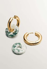 Pendientes de aro dorados que presentan una piedra de mármol blanco y verde. Uno tiene un acento de piedra circular; el otro es un aro liso y redondeado.