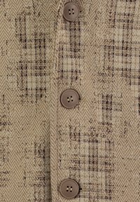 Chaqueta de tela en patrón de espiga beige con acentos de cuadros marrones. Presenta cuatro botones marrones a lo largo del cierre frontal.