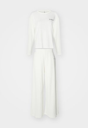 Valkoinen teksturoitu pitkähihainen paita, jossa on pyöreä pääntie, ja siihen sopivat leveät housut, joissa on joustava vyötärö ja hienovarainen embroidery-yksityiskohta.