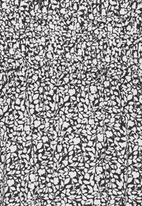 Tessuto nero con un piccolo motivo floreale bianco e una texture arricciata. Il tessuto è leggero e scorre con dettagli plissettati.