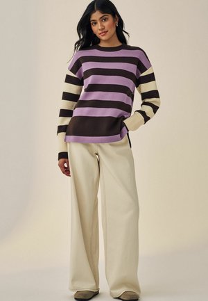 Gestreepte trui in lavendel, bruin en crème, met een losse pasvorm en geribbelde mouwen, gecombineerd met wijde crème broek.