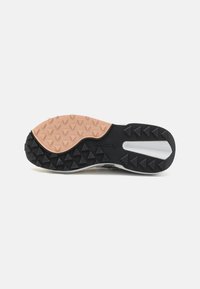 Suola di scarpe sportive in gomma nera e beige con battistrada triangolare, caratterizzata da un'intersuola bianca e dal marchio in rilievo "Saucony."