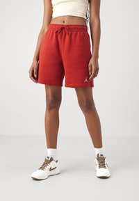Shorts en mélange de coton rouge avec une taille élastique et un cordon de serrage, présentant un petit logo Jordan blanc sur la cuisse gauche.