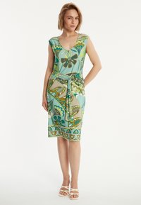 Robe à motifs floraux avec un décolleté en V profond, des manches courtes, une taille cintrée et une longueur au genou. Les couleurs incluent des verts, des bleus et du beige.