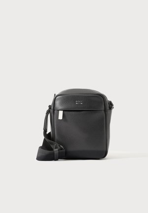 Sort tekstureret læder crossbody taske med frontlomme og justerbar rem, vist på en ensartet lys baggrund.