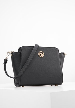 Bolso bandolera negro con textura, emblema de logo dorado, correa desmontable y herrajes dorados sobre una superficie blanca.