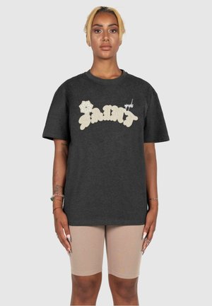 Dark gray cotton T-shirt with prominent cream-colored "SAINT" lettering and flower graphic, featuring a relaxed fit and short sleeves.