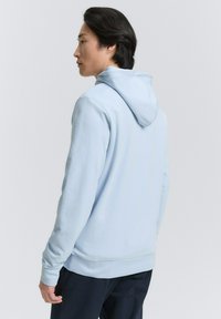 Világoskék kapucnis pulóver, puha tapintással és kenguruzsebbekkel. Megjelenése állítható kapucni és bordázott mandzsetták, valamint alsó szegés. Egyszerű, hétköznapi dizájn.