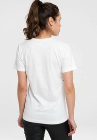 Weißes Baumwoll-T-Shirt mit kurzen Ärmeln, Rundhalsausschnitt, glatter Textur und geradem Schnitt. Der Hintergrund ist schlicht und hell gefärbt.