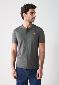 Grijze t-shirt met korte mouwen in Henley-stijl, gemaakt van zacht materiaal, met een ronde hals en een klein geel logo op de borst.