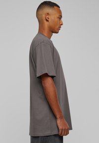 T-shirt gris à manches courtes en coton doux, offrant une coupe décontractée et un design classique à col rond. Détails de couture aux manches et à l'ourlet.