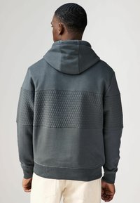 Grijze hoodie met een gestructureerd hexagonaal patroon op de bovenrug en mouwen, met een aansluitende zoom en verstelbare capuchon.