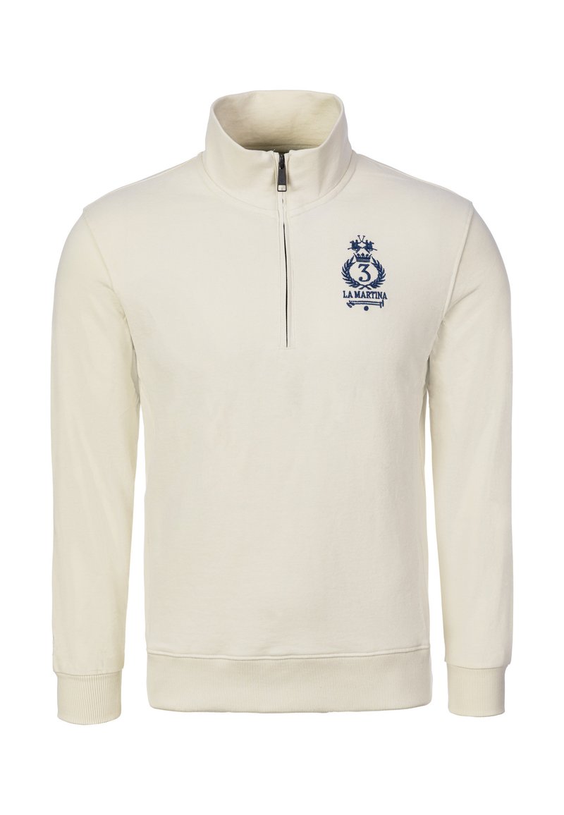 Sudadera crema con cremallera y cuello alto, puños y cintura acanalados. Presenta un logo azul marino con una corona y el número "3".