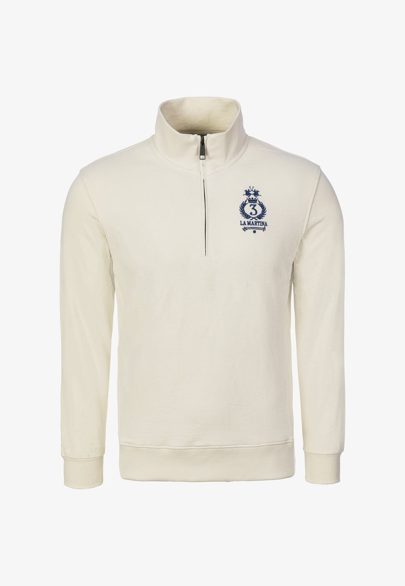 Sudadera crema con cremallera y cuello alto, puños y cintura acanalados. Presenta un logo azul marino con una corona y el número "3".