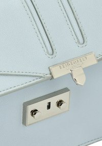 Borsa a tracolla in pelle testurizzata blu chiaro con una chiusura metallica argento e finiture lucidate, dotata di due borchie esagonali.