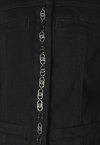 Jaqueta de ganga preta com um detalhe central em corrente metálica, alternando entre accents pretos e prateados, e dois bolsos frontais.