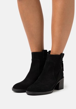 Mustat mokkanahkaiset nilkkurit paksulla korolla, joissa on sivulla joustavat paneelit ja vetonauha takana helppoa pukemista varten. Liukas pohja.