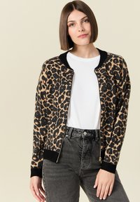 Cardigan con stampa leopardata in morbido tessuto strutturato, con colletto e polsini a costine neri, dotato di zip frontale e sfondo beige.