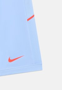 Šviesiai mėlynos sportinės šortai su mažuoju raudonu Nike swoosh logotipu ir raudonu akcentu kvėpuojančio tinklinio panelėje.
