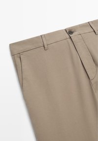 Beige Hosen aus Baumwolle mit flachem Frontdesign, Reißverschluss, Gürtelschlaufen und zwei Seiten Taschen. Glatte Textur ohne sichtbare Muster.