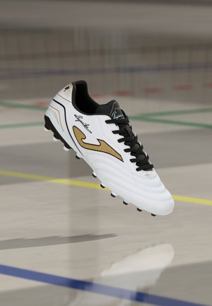 Scarpetta da calcio bianca con dettagli dorati, lacci neri e superfici testurizzate. Presenta un logo distintivo e un design con punta arrotondata.