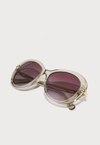 Ochelari de soare mari, cu lentile violet cu gradient, ramă transparentă și accente din aur. Dispune de un detaliu mic de piatră prețioasă pe margine.
