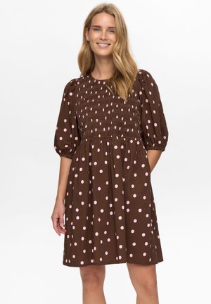 Brązowa sukienka w groszki z marszczonym gorsetem, bufkami i rozkloszowanym dołem. Wzór różowych groszków na ciemnym tle.