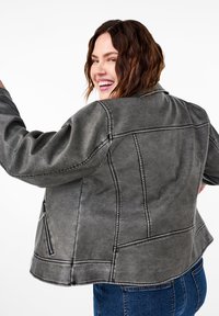 Giacca grigia, con texture, dotata di colletto, chiusura zip e cuciture a contrasto, caratterizzata da una vestibilità rilassata e tasche laterali angolate.