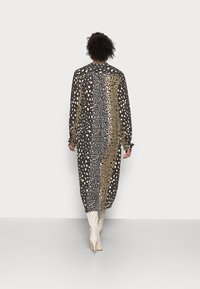 Długa, wzorzysta sukienka z mieszanką nadruków zwierzęcych w kolorach czarnym, złotym i niebieskim. Wykonana z lekkiego materiału, z elastycznymi mankietami i luźnym krojem.