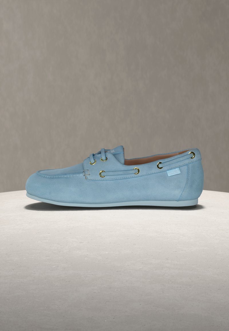 Ανοιχτό γαλάζιο δερμάτινο μοκασίνι με χρυσά μεταλλικά κουμπώματα, πλαϊνή διακόσμηση με κορδόνια και χαμη λή γόμα, εμφανιζόμενο από το εξωτερικό πλάι σε ουδέτερο φόντο.