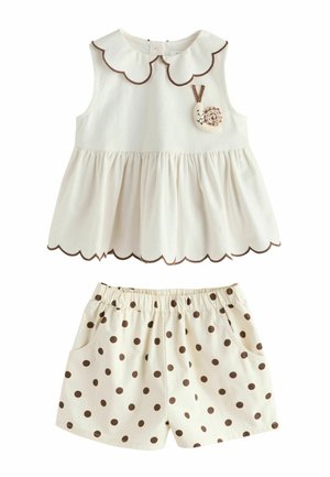 Kremowy top bez rękawów z falowanymi krawędziami i aplikacją ślimaka, zestawiony z kremowymi szortami z elastyczną talią, brązowymi grochami i kieszeniami.