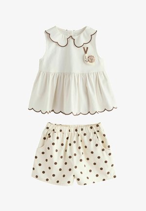 Ærmeløs cremefarvet top med bølgede kanter og snegl-applikation, kombineret med cremefarvede shorts med elastik i taljen, brunprikkede og med lommer.