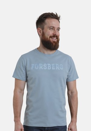 Camiseta azul claro de textura suave con la palabra "FORSBERG" en un acabado brilloso en el pecho. Diseño de mangas cortas y cuello redondo.