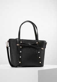 Sort clutch lavet af tekstureret materiale, med en sløjfe detalje, perle accenter, dobbelte håndtag og en justerbar rem.