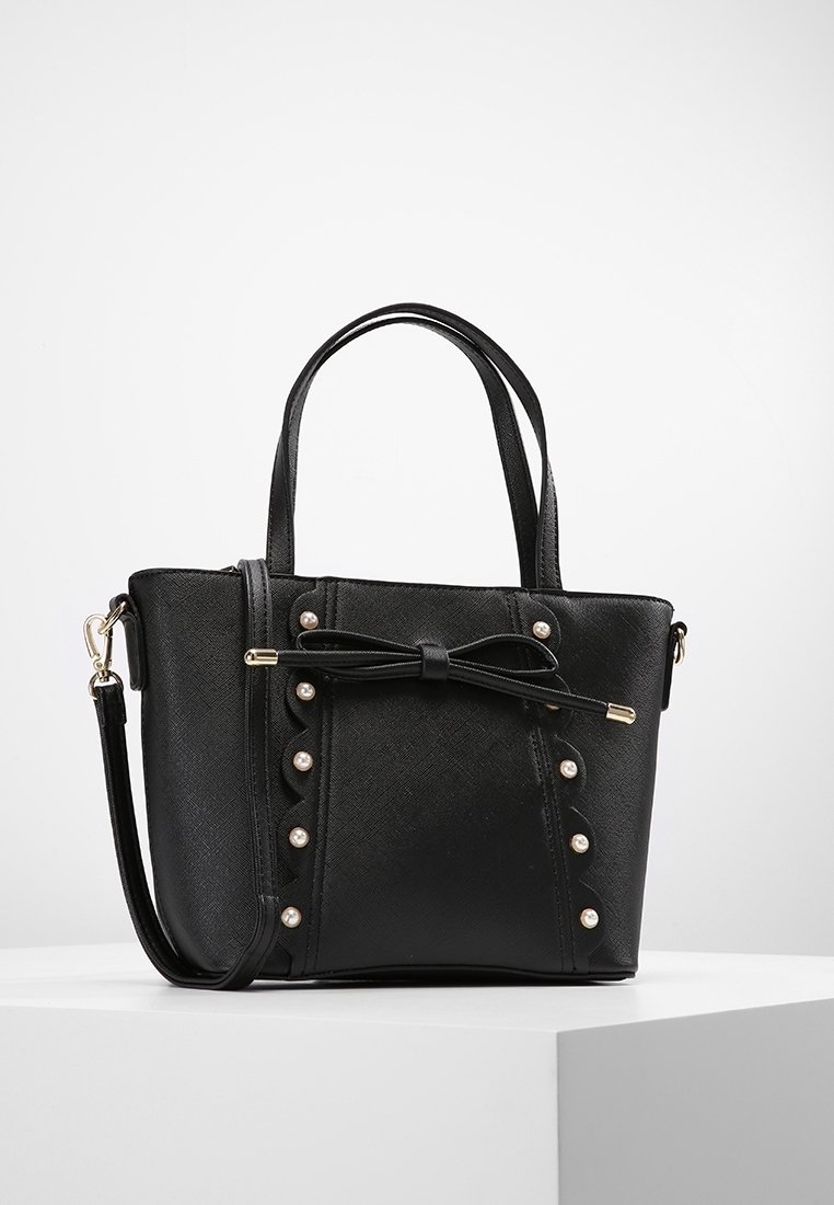 Sort clutch lavet af tekstureret materiale, med en sløjfe detalje, perle accenter, dobbelte håndtag og en justerbar rem.