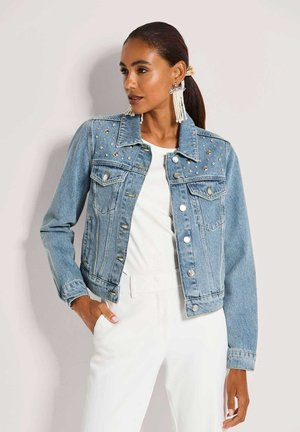 Jeansjacke aus hellblauem Stoff, verziert mit metallischen Nieten auf den Schultern, mit klassischem Kragen und Knopfverschluss.