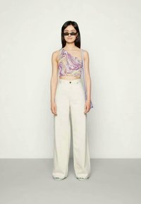 Top sem mangas de várias cores com um design ondulante roxo e amarelo; combinado com calças largas brancas de cintura alta. Acessórios: óculos de sol pequenos e pretos.