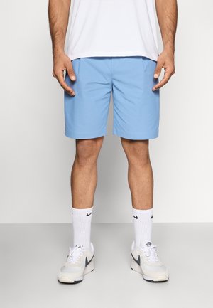 Jasnoniebieskie szorty o prostym kroju, wykonane z gładkiej tkaniny, z bocznymi kieszeniami i płaskim paskiem, noszone z białą koszulą i trampkami.