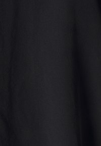 Tessuto nero con una superficie liscia e una leggera lucentezza. Nessun motivo o disegno visibile; la superficie appare uniforme ed omogenea.