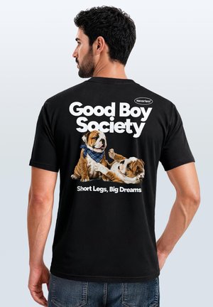 Man wearing black T-shirt with two playful bulldog puppies and text "Good Boy Society, Short Legs, Big Dreams" on the back.