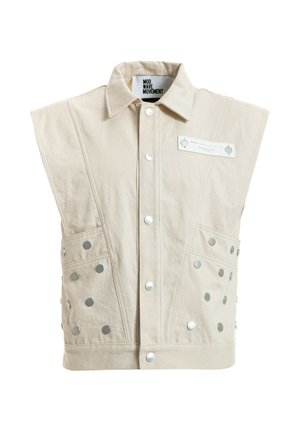 Chaqueta sin mangas beige con botones de presión en la parte delantera, dos bolsillos laterales con tachuelas metálicas, cuello ancho y etiqueta que dice "MOD WAVE MOVEMENT."