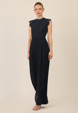 Zwarte kanten jumpsuit met een aansluitende lijfje en kapmouwtjes, en een geplooide broek met wijde pijpen. Gladde stof met verfijnde kantdetails.