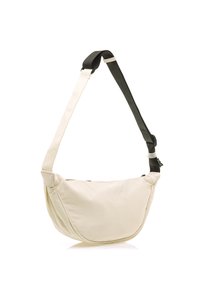 Bolso de hombro de tela crema con forma curvada, correa negra ajustable y cierre con cremallera. Textura suave y diseño minimalista.