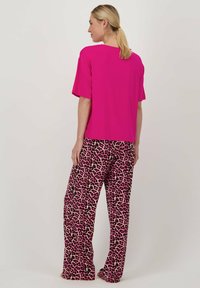 Roze T-shirt met korte mouwen, gecombineerd met losvallende broek met luipaardprint in roze, zwart en beige. Soepele stof, relaxed fit.
