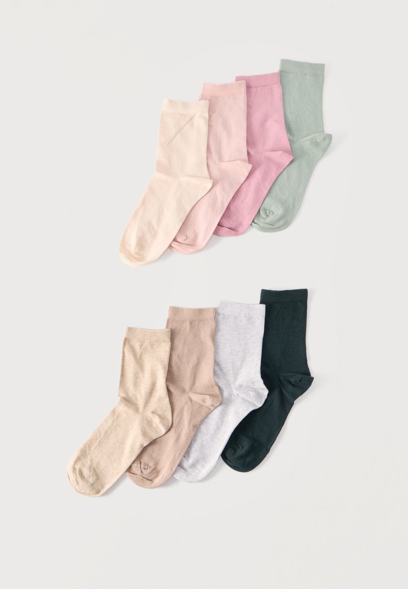 Huit paires de chaussettes basses pliées disposées en deux rangées, présentant des couleurs pastel et neutres telles que rose, vert, beige, gris et vert foncé.